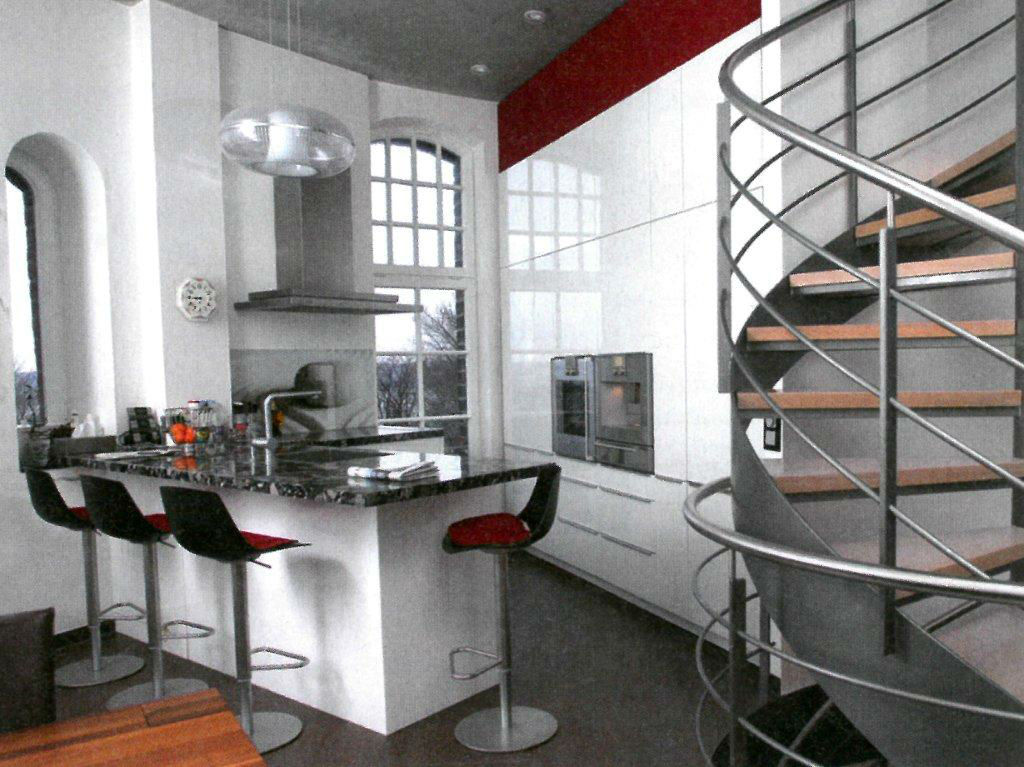 Moderne Küche in hochwertigem Design, nebenan eine Edelstahltreppe mit Holzstufen